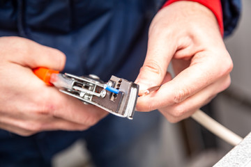 A man works with a wire stripper in his hands and a cable. Hands only. Horizontal orientation.