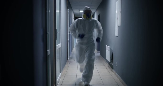 Men in hazmat suit running through a corridor