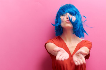 studio portrait of a sexy beautiful girl with a smile in motion on a pink background. Girl with blue hair