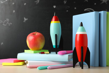 Bright toy rockets and school supplies on wooden table