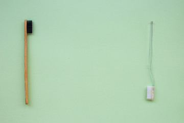 Two toothbrushes: natural bamboo and plastic on a green paper background. The concept of choice in favor of informed consumption