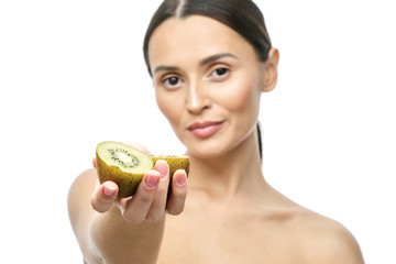 A close-up portrait of a girl with clear skin and a kiwi fruit in her hands