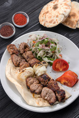 grilled meat on pita bread with salad on a black wooden background