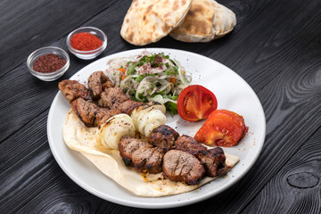 grilled meat on pita bread with salad on a black wooden background