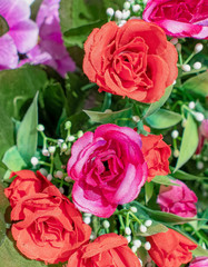 red and violet colored roses on green foliage, artficial flowers bouquet top view close up