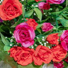 red and violet colored roses on green foliage, artficial flowers bouquet top view close up