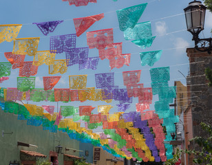 "Papel picado" is a decorative craft made by cutting elaborate designs into sheets of tissue paper, common themes include birds, floral designs, and skeletons