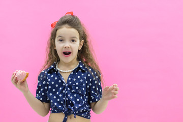Funny smiling little girl with colorful donut on empty background.