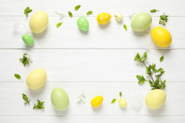 Frame made with Easter eggs on white wooden background, flat lay. Space for text
