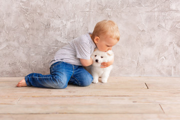 Cute little baby boy playing with little white puppy