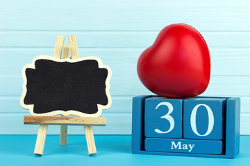 wooden calendar with the date of May 30 on a wooden background and a sign for text, 
International...