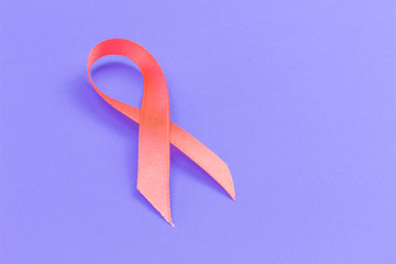 orange ribbon symbolizing International Day of Multiple Sclerosis on a purple background, copy...