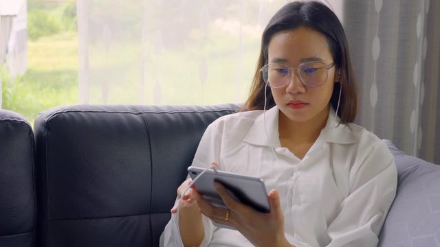 An Asian woman is working online via a tablet device. Working At Home