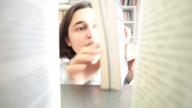 Young woman choosing book in library