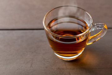 Close up hot tea cup on wood table . hot tea in handle glass with copy space for text or design.