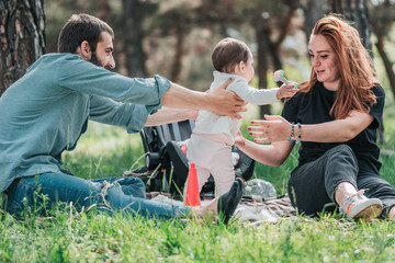 Family, child, childhood and parenthood concept - Happy little baby with parent learning to walk. Mother and Father support and help her. Outdoor, on picnic in forest.