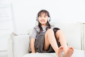坐在沙发上带着耳机的亚洲小女孩