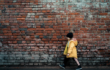 A girl poses against a brick wall. Young model.