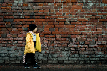 A girl poses against a brick wall. Young model.