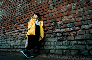 Fototapeta na wymiar A girl poses against a brick wall. Young model.