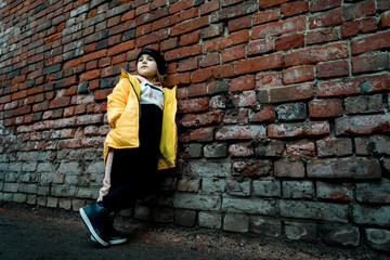 Fototapeta na wymiar A girl poses against a brick wall. Young model.