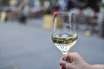 Wine and dine, woman holding a wine glass with white wine and city reflection on the wine. Cool reflections with blurry background.