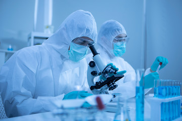 Scientist looking through a microscope in a laboratory. Discovery vaccine COVID19