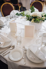 Table for guests on a wedding, there are fresh flowers, cutlery and crockery, emty Menu card