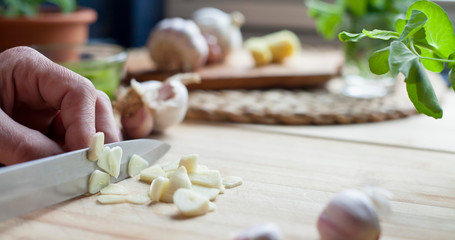 Chopping garlic activity -  male cook is slicing the garlic cloves.