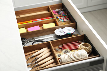 Fototapeta na wymiar Sewing accessories and stationery in open desk drawer indoors