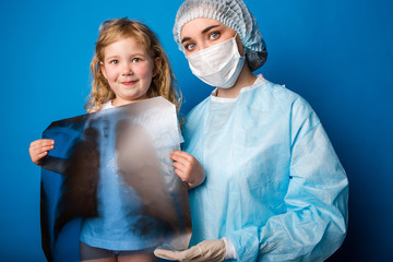 Doctor woman in uniform with little girl holding chest x-ray standing on blue background