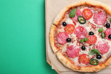 Delicious pizza Diablo in cardboard box on green background, top view. Space for text