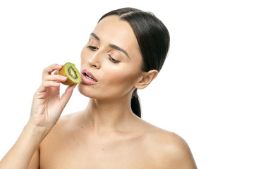 close-up portrait of a girl with clear skin holding a kiwi fruit to her face on a white background