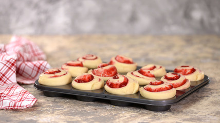 Raw yeast buns with berry jam in a baking dish.