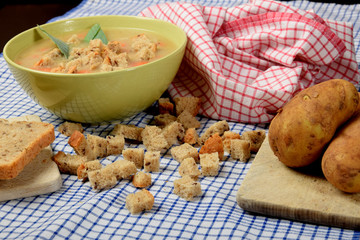 home-made soup made of vegetables in a green bowl with pieces of dry bread