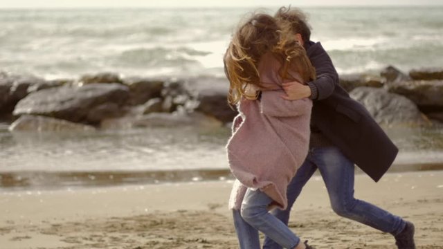 Man running chasing girlfriend on beach happy after end of quarantine in love