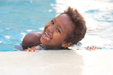 Little african child splashing out in the pool