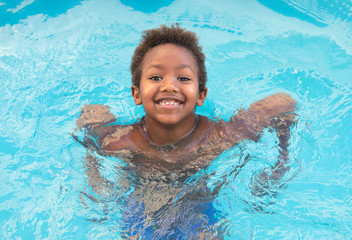 Fototapeta na wymiar Little african child splashing out in the pool