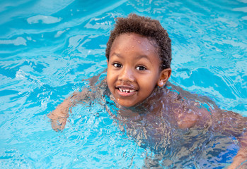 Little african child splashing out in the pool