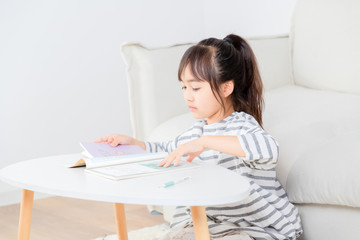 Asian little girl sitting on the carpet writing homework