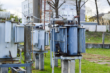 Large industrial iron metal transformer substation with transformers and high-voltage electrical equipment and wires with surge arresters to supply the city with electricity