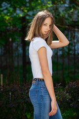 Fototapeta premium Portrait of a young blonde girl in white t-shirt and blue jeans