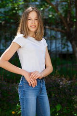 Fototapeta premium Portrait of a young blonde girl in white t-shirt and blue jeans