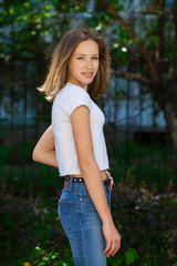 Naklejka na ściany i meble Portrait of a young blonde girl in white t-shirt and blue jeans