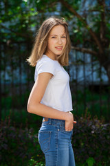 Fototapeta premium Portrait of a young blonde girl in white t-shirt and blue jeans