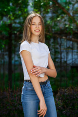Fototapeta premium Portrait of a young blonde girl in white t-shirt and blue jeans