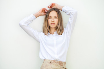 Fototapeta premium Young blonde girl in white blouse - isolated on white wall background