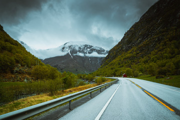 Asfaltowa droga prowadząca między wysokimi ośnieżonymi górami