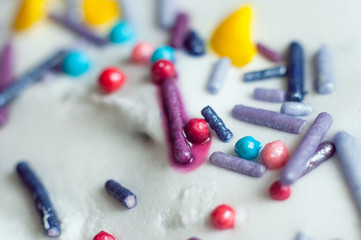 Multi-colored sweet pastry topping in white glaze decorates pastries. Close-up, macro shot.