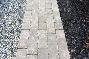 Tumbled paver walkway with wood chip and pea gravel mulches create a low maintenance landscaping...